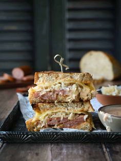 two sandwiches stacked on top of each other next to a bowl of soup and bread