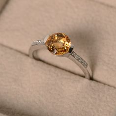 This ring features a 7mm round cut natural citrine and sterling silver finished with rhodium. Customization is available. It is made by hand, and it will take about 7 days to finish the ring after your payment is completed. Main stone: genuine citrine Citrine weight: Approx 1.40 ct Metal type: sterling silver finished with rhodium Accent stone: cz Customization is available, I also can make it with 14k solid gold (white or yellow or rose) and diamond accent stone, just feel free to contact me. A Citrine Topaz Promise Ring, Classic Yellow Citrine Birthstone Ring, Fine Jewelry Sapphire Ring With Citrine Accent Stones, Citrine Center Stone Topaz Ring, Classic Citrine Rings With Accent Stones, Orange Round Jewelry With Brilliant Cut, Fine Jewelry Citrine Topaz Ring With Accent Stones, Classic Yellow Sapphire Jewelry Promise Ring, White Gold Citrine Birthstone Ring With Gemstone