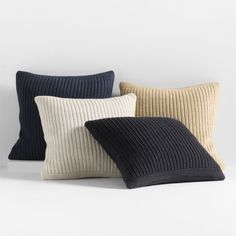 four pillows in various colors and sizes on a white surface with one black, the other beige