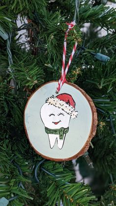 a wooden ornament with a tooth on it hanging from a christmas tree branch