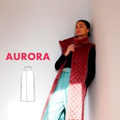 a woman standing next to a wall wearing a red vest and blue pants with the word aurora written on it