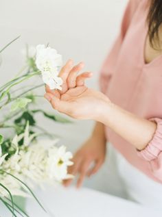 a woman holding a bouquet of flowers with her hands on top of the bride's dress