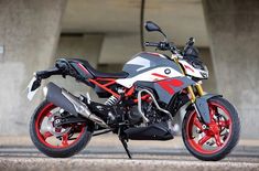 a white and red motorcycle parked in front of an overpassed area with concrete