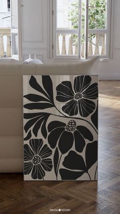 a black and white flowered box sitting on top of a hard wood floor