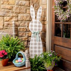 a wooden bunny statue sitting on top of a table next to potted plants and flowers