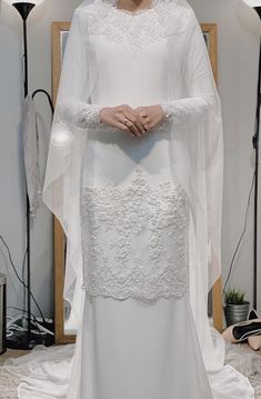 a woman in a white wedding dress standing next to a mirror with her hands on her hips