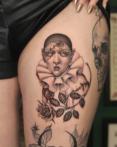 a woman's thigh with tattoos on it and a skull in the back ground