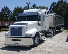 a large white truck parked on top of a gravel road