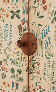 an old door handle is attached to a floral wallpaper