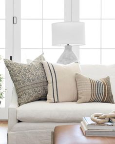 a living room filled with furniture and pillows on top of a white couch next to a window