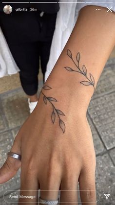 a woman's hand with a tattoo on her left wrist and an olive branch on the right wrist