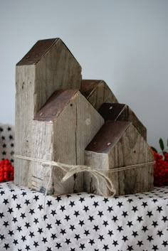 two wooden houses sitting on top of a black and white table cloth with red berries in the background