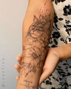 a woman's arm with a cat and flowers tattoo on the left side of her arm