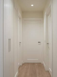 an empty hallway with white walls and wooden floors