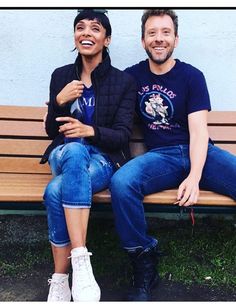 two people sitting on a bench smiling for the camera