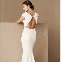 a woman in a white dress is leaning against a wall with her back to the camera