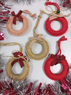 four rope wreaths with bows and ribbons hanging from them on tinsel wrapped tinsel