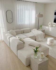 a large white couch sitting in a living room next to a tv mounted on a wall