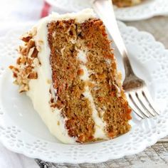 a slice of carrot cake on a white plate with a fork and napkin next to it