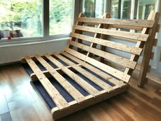 a wooden bed frame sitting on top of a hard wood floor next to a window