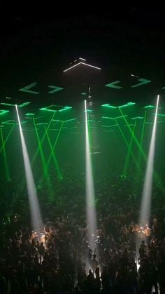 a large group of people standing in front of green and white lights at a concert