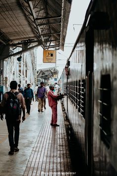 people are walking on the platform next to a train