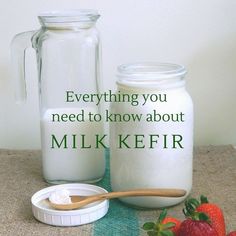 there are two jars with milk and strawberries on the table