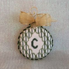 a christmas ornament with a bow on it's head and letter c in the center