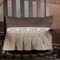 a chair with a pillow on top of it and a plaid blanket behind the chair