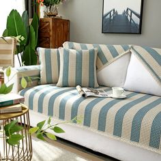 a couch with blue and white striped covers in a living room next to a window