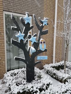 a tree that has been decorated with blue stars and an owl on it in front of a brick building