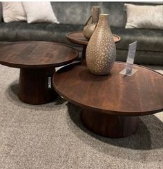 two wooden tables sitting on top of a carpeted floor next to a gray couch