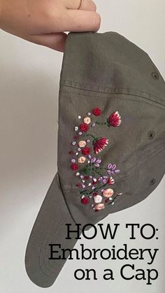 a hat with embroidered flowers on it being held by a person's hand and the words how to embroidery on a cap