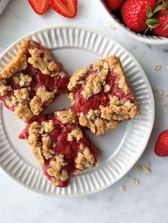 strawberry crumb bars on a plate next to strawberries