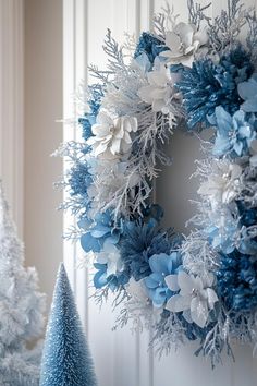 a blue and white christmas wreath hanging on a wall next to two small fir trees