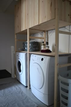 a washer and dryer in a room with wooden shelvings on the wall