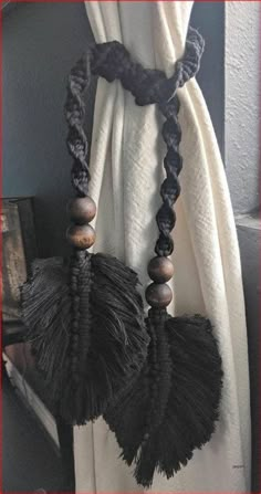 a black and white curtain with tassels hanging from it's side in front of a window