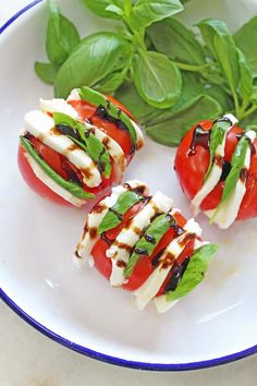 four tomatoes with mozzarella and spinach leaves on a white plate