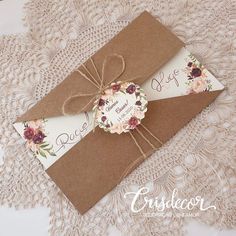 an envelope with a tag tied to it on top of lace doily and paper