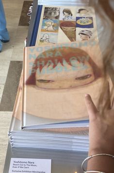 a person pointing at a book on top of a table with pictures and stickers