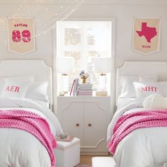 two white beds with pink blankets and pillows in a small room next to a window