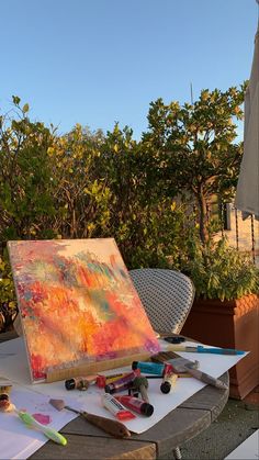 an artist's easel sitting on top of a table covered in art supplies