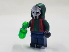 a lego figure holding a green bottle with a skull on it's face and wearing a hood