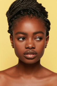 a woman with braids on her head and brown eyes, wearing an off - white top