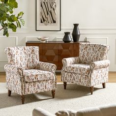 two chairs sitting next to each other on top of a white rug in front of a wooden dresser