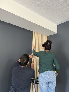 two people are painting the walls in a room