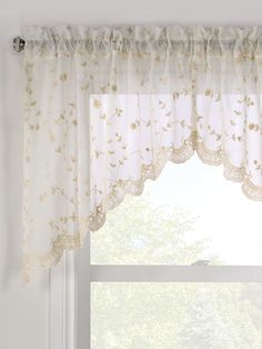 a window with white curtains and flowers on the valance, in front of a large window