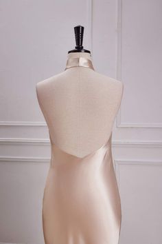 the back of a mannequin dress on display in front of a white wall