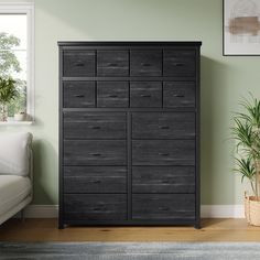 a large black dresser in a room with a white couch and potted plant next to it