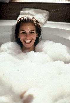 a woman smiles as she takes a bubble bath